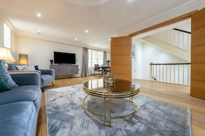 A modern living room with a sofa, a coffee table, and a flat-screen TV. - Exquisite 3-bedroom House in Mayfair (London)