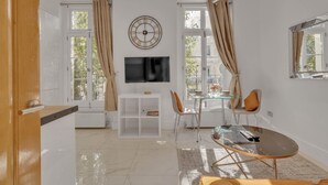 Ein modernes Wohnzimmer mit Flachbildfernseher, einem Glastisch und einem Essbereich mit Stühlen und einem Glastisch.