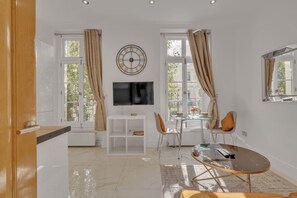 Ein modernes Wohnzimmer mit Flachbildfernseher, einem Glastisch und einem Essbereich mit Stühlen und einem Glastisch.