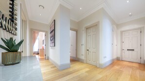 A hallway with wooden flooring, white walls, and doors. - Superior 2 Bedroom Apartment in Mayfair (London)