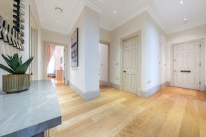 A hallway with wooden flooring, white walls, and doors. - Superior 2 Bedroom Apartment in Mayfair (London)