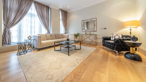 A modern living room with a sofa, a coffee table, a console table, and a lamp. - Superior 2 Bedroom Apartment in Mayfair (London)