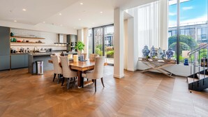 A modern kitchen with a dining area, large windows, and a view of the outdoors. - Luxury 4-bed Duplex Penthouse in Battersea (London)