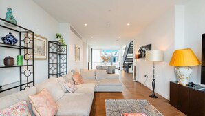 A modern living room with a sofa, coffee table, and decorative items. - Luxury 4-bed Duplex Penthouse in Battersea (London)
