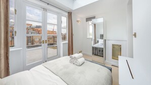 Ein modernes Hotelzimmer mit einem großen Bett, einem Oberlicht, Blick auf die Stadt und einem Kamin.