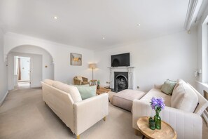 A spacious living room with a fireplace, two sofas, a coffee table, and a television. - Modern 4-bed Apartment in Knightsbridge (London)