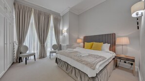 Una camera d'albergo con un letto grande, due comodini, una sedia, una scrivania e una lampada.