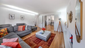 Una sala moderna con un sofá seccional gris, una mesa de centro blanca y una alfombra roja.