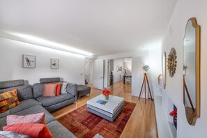 Ein modernes Wohnzimmer mit einem grauen Ecksofa, einem weißen Couchtisch und einem roten Teppich.