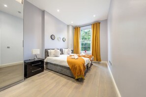 Ein modernes Schlafzimmer mit Bett, Nachttisch und einem Fenster mit Vorhängen.