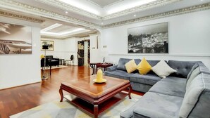 A spacious living room with a grey sofa, a wooden coffee table, and a large painting on the wall. - Superior Three Bedroom Apartment Opposite Harrods (London)