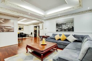 Ein geräumiges Wohnzimmer mit einem grauen Sofa, einem Holztisch und einem großen Gemälde an der Wand.