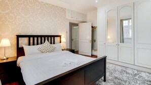 A bedroom with a bed, nightstands, a wardrobe, and a mirror. - Superior Three Bedroom Apartment Opposite Harrods (London)