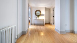 A hallway with a radiator, a mirror, and a lamp on a console table. - Super Deluxe 2 Bedroom Apartment in Mayfair (London)