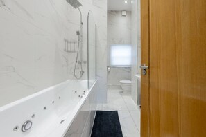 Ein modernes Badezimmer mit einer Duschkabine aus Glas, einer weißen Badewanne und einem WC.