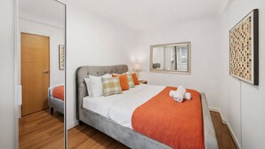 Une chambre d’hôtel avec un lit, un miroir, une œuvre d’art murale et une porte en bois.