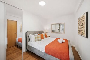 Ein Hotelzimmer mit einem Bett, einem Spiegel, einem Wandbild und einer Holztür.