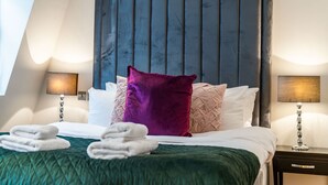 A hotel room with a bed, pillows, a headboard, a nightstand, and a lamp. - Royal Two Bedroom House in Mayfair (London)