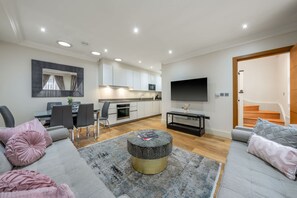 Ein modernes Wohnzimmer mit einer Couch, Hocker und einem Essbereich mit Stühlen und einem Tisch.