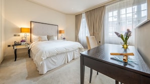 Et hotelværelse med seng, sengeborde, et skrivebord og et vindue med gardiner.