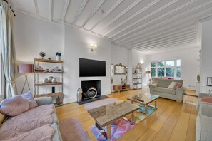 A living room with a fireplace, sofa, coffee table, and TV. - Superior 3 Bedroom Apartment in Belgravia w Patio (London)