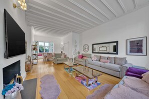 A spacious living room with a flat-screen TV, a sofa set, a coffee table, and a fireplace. - Superior 3 Bedroom Apartment in Belgravia w Patio (London)