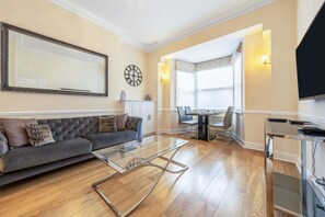 Ein Wohnzimmer mit einer Couch, einem Glastisch und einem Essbereich mit Stühlen und einem Tisch.