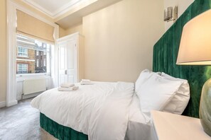 Ein Hotelzimmer mit Bett, Fenster, Heizkörper und einer grünen Wand.
