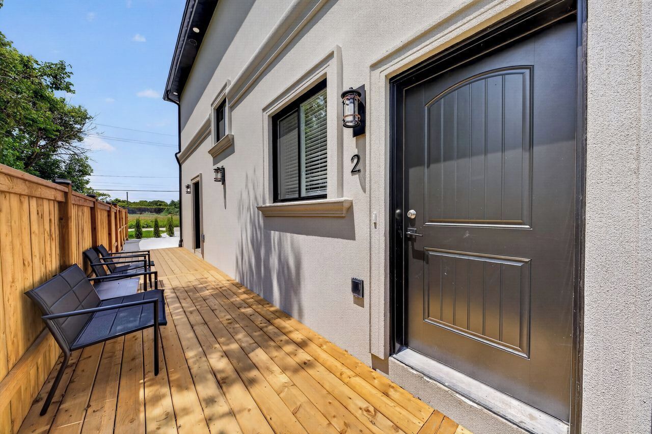 Une maison avec une terrasse en bois, une porte noire et le chiffre « 2 » peint sur le mur.