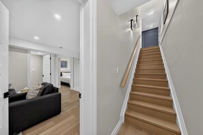 Un interior modern amb una escala, un sofà i un llit en un passadís.
