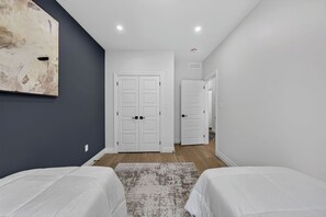 Un dormitori amb dos llits, un quadre abstracte gran i un passadís que condueix a una altra habitació.