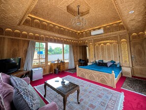 Una habitación con cama, televisión, escritorio y candelabro.