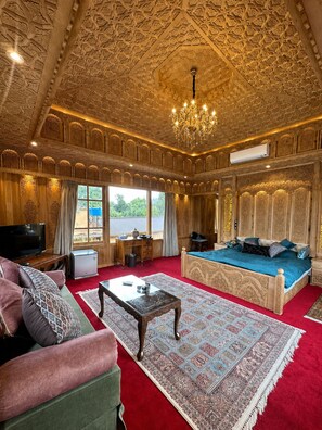 Una habitación con paneles de madera elaborados, una cama grande, un sofá, un televisor y una alfombra estampada.