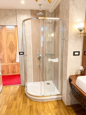 Un baño moderno con cabina de ducha de vidrio, tocador de madera y paredes de mármol.
