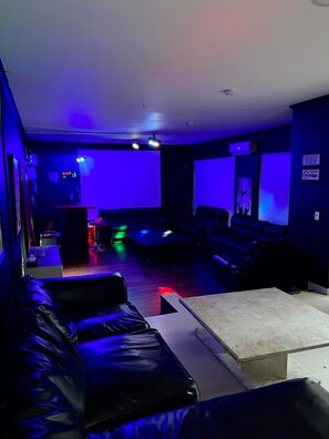 A dimly lit room with a bar area, a couch, and a table.