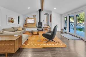 A modern living room with a sofa, armchair, coffee table, fireplace, and large windows. - Stylish home in Historic Forest Park perfect for a family retreat (Birmingham)