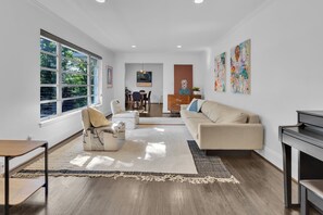A modern living room with a sofa, a coffee table, a dining area with chairs, and artwork on the walls. - Stylish home in Historic Forest Park perfect for a family retreat (Birmingham)