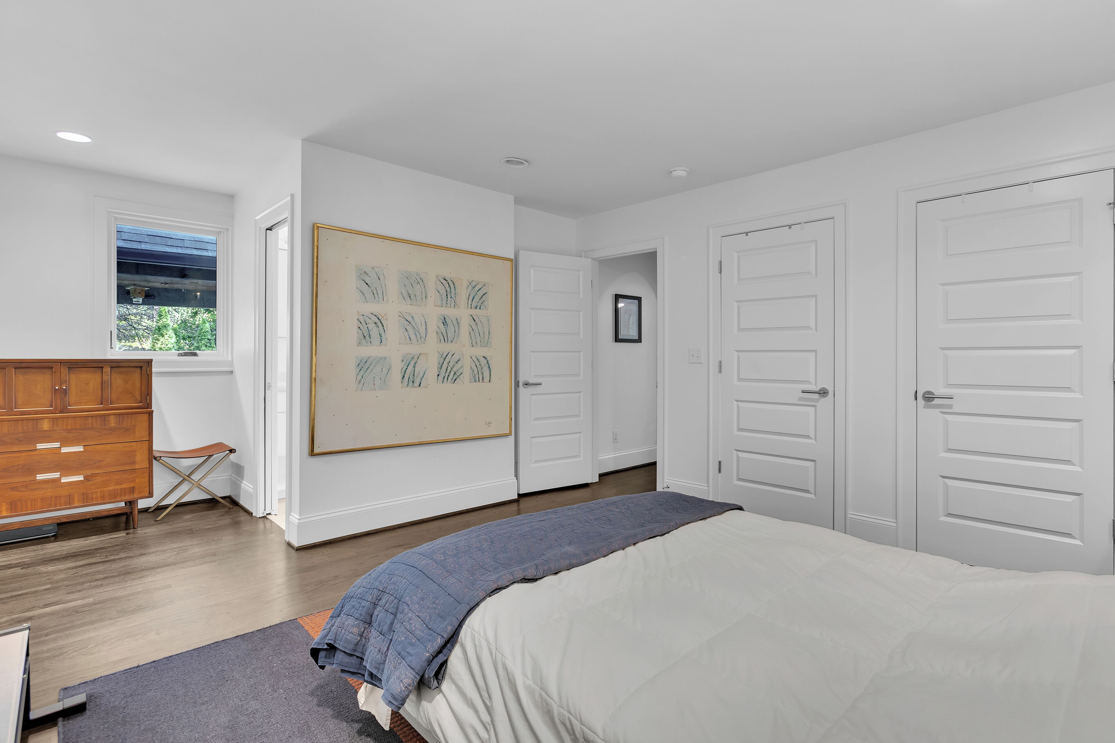 A bedroom with a bed, a dresser, a window, and a door.