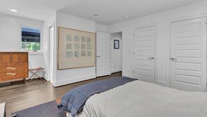 Ein Schlafzimmer mit Bett, Kommode, Fenster und Tür.