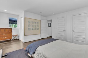 A bedroom with a bed, a dresser, a window, and a door. - Stylish home in Historic Forest Park perfect for a family retreat (Birmingham)