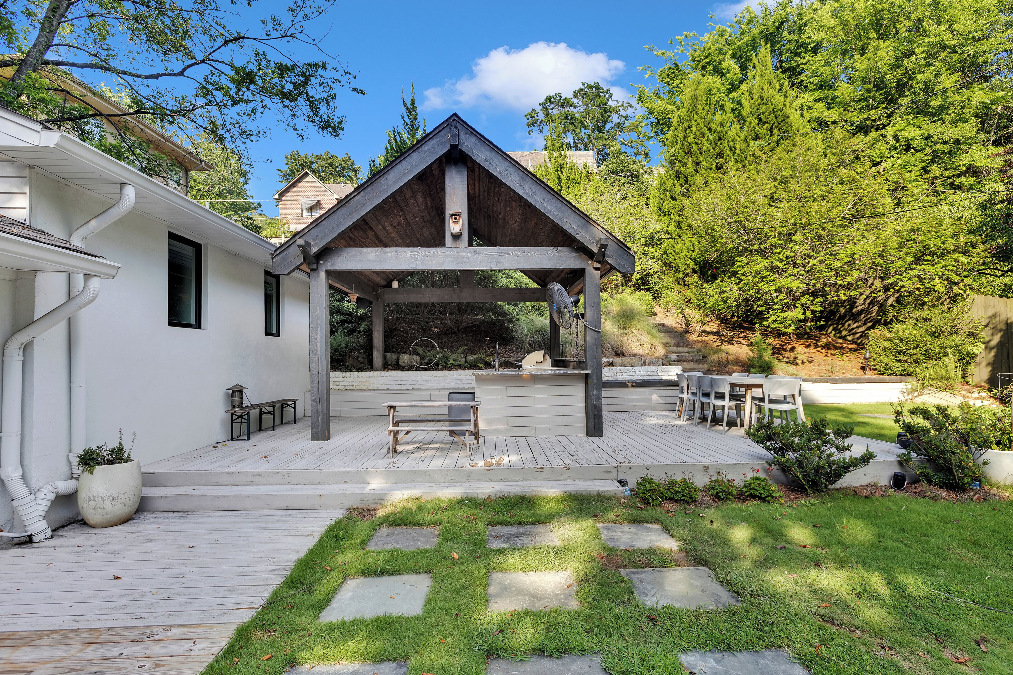 A covered patio with a wooden roof, stone steps, and a bench.