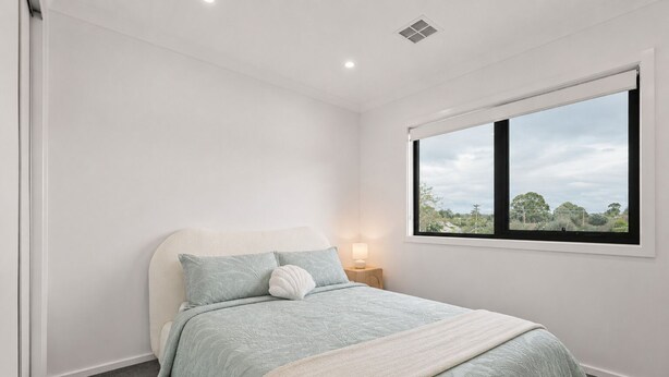 A bedroom with a bed, a bedside lamp, a window, and a view of the outdoors. - The Cowes Retreat by Ready Set Stay (Cowes)