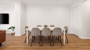 A dining area with a white table, six chairs, a green mug, a potted plant, and a flat-screen TV on the wall. - The Cowes Retreat by Ready Set Stay (Cowes)