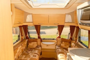 A campervan interior with a central seating area, a small table, and a TV mounted on the wall.