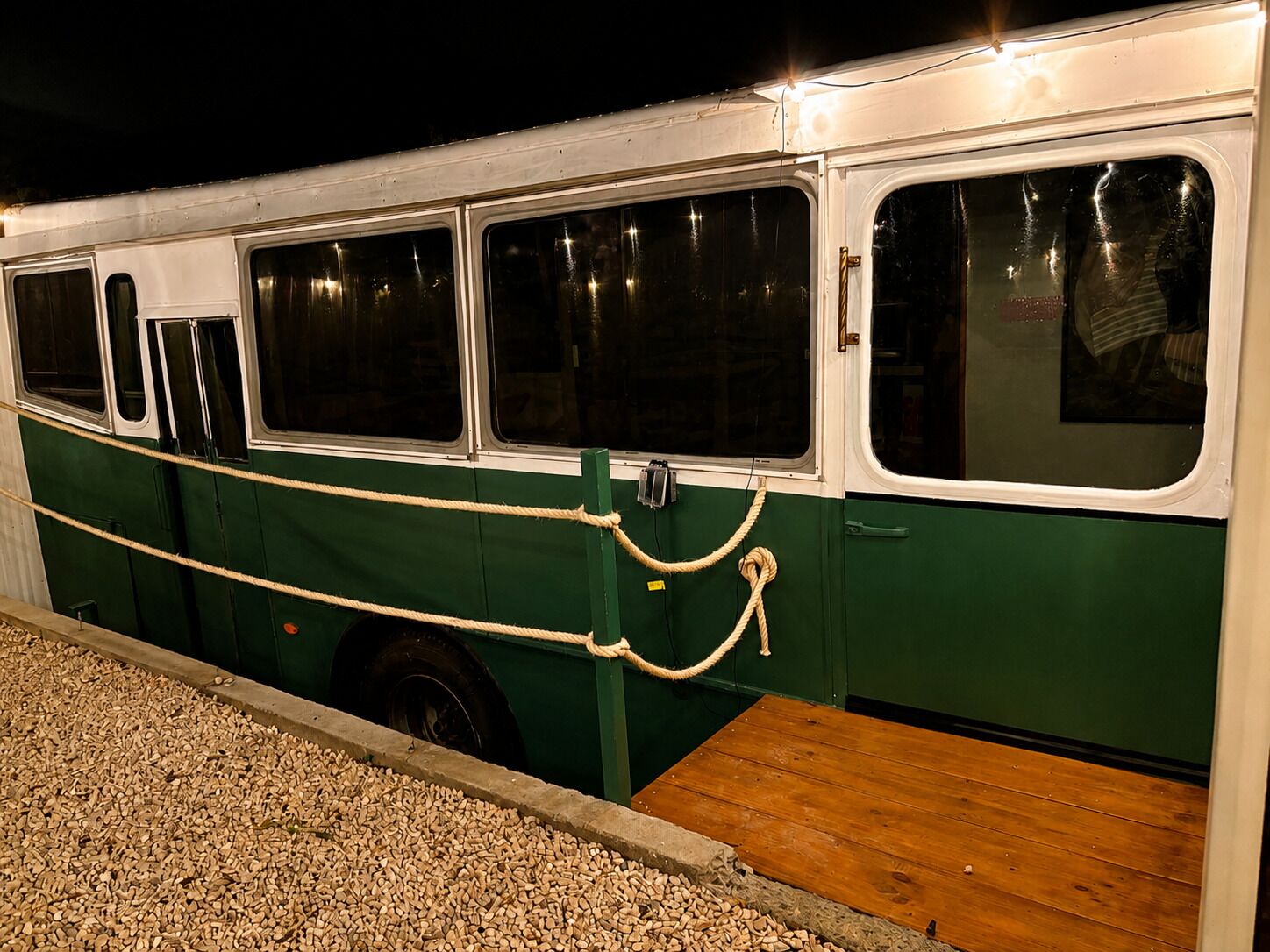 Ein stehender Bus mit mehreren Fenstern, gesichert durch ein Seil an einer Holzplattform.