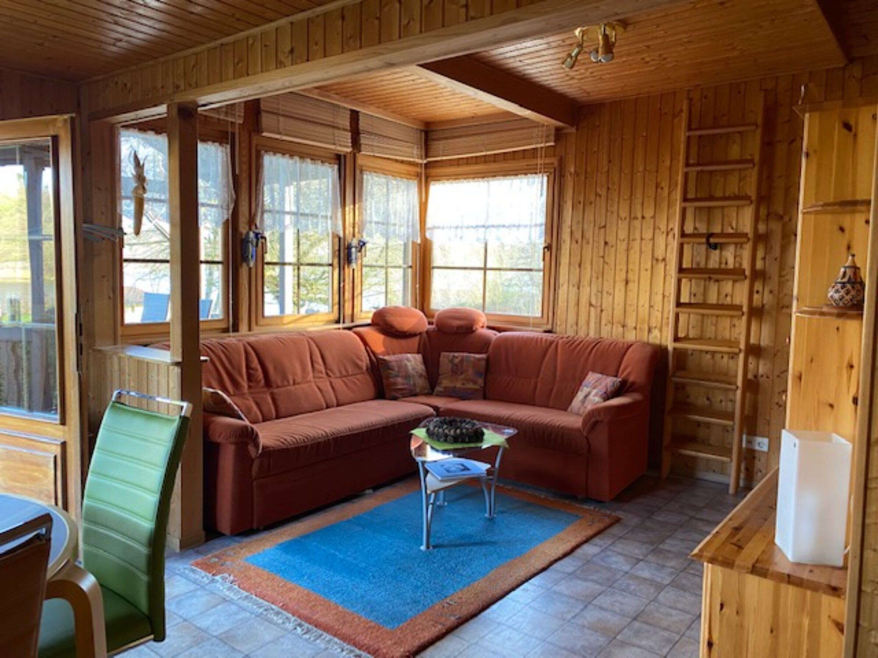 A wooden interior with a sectional sofa, a small table, and a chair.