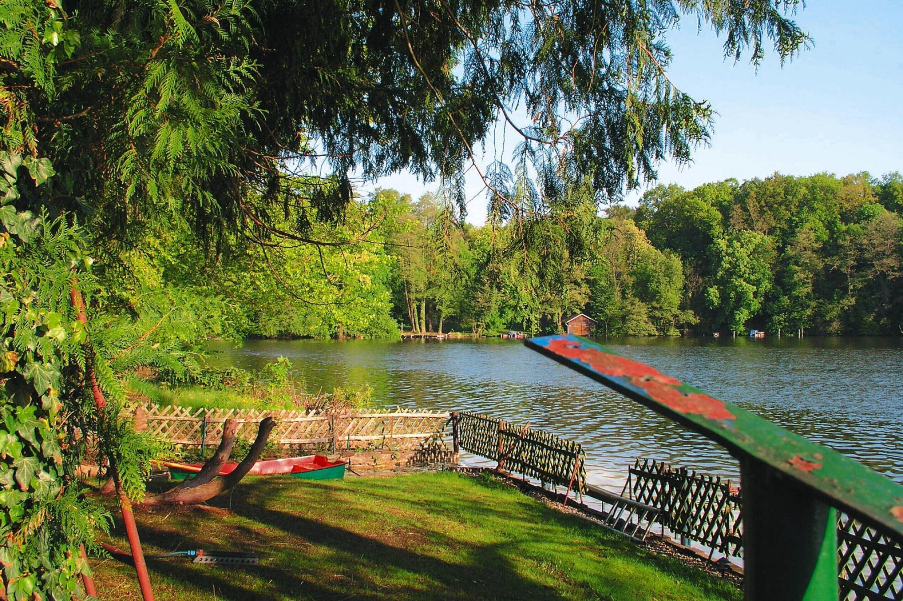 Una vista tranquila de un lago con un muelle de madera y un bote pequeño.