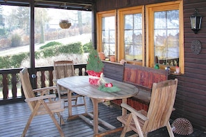 A wooden deck with a round table and four chairs, overlooking a snowy landscape. - Blockhaus am Templiner See mit Seeblick (Templin)