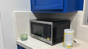 Eine Küche mit Mikrowelle, Spülmittel und blauen Schränken.