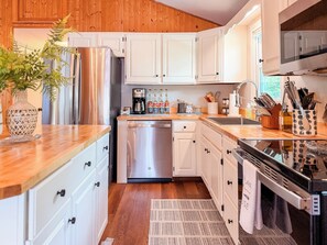 A modern kitchen with white cabinets, stainless steel appliances, and wooden countertops. - Lakefront Escape - Dock, Beach, Grill & Hot Tub (Milton)